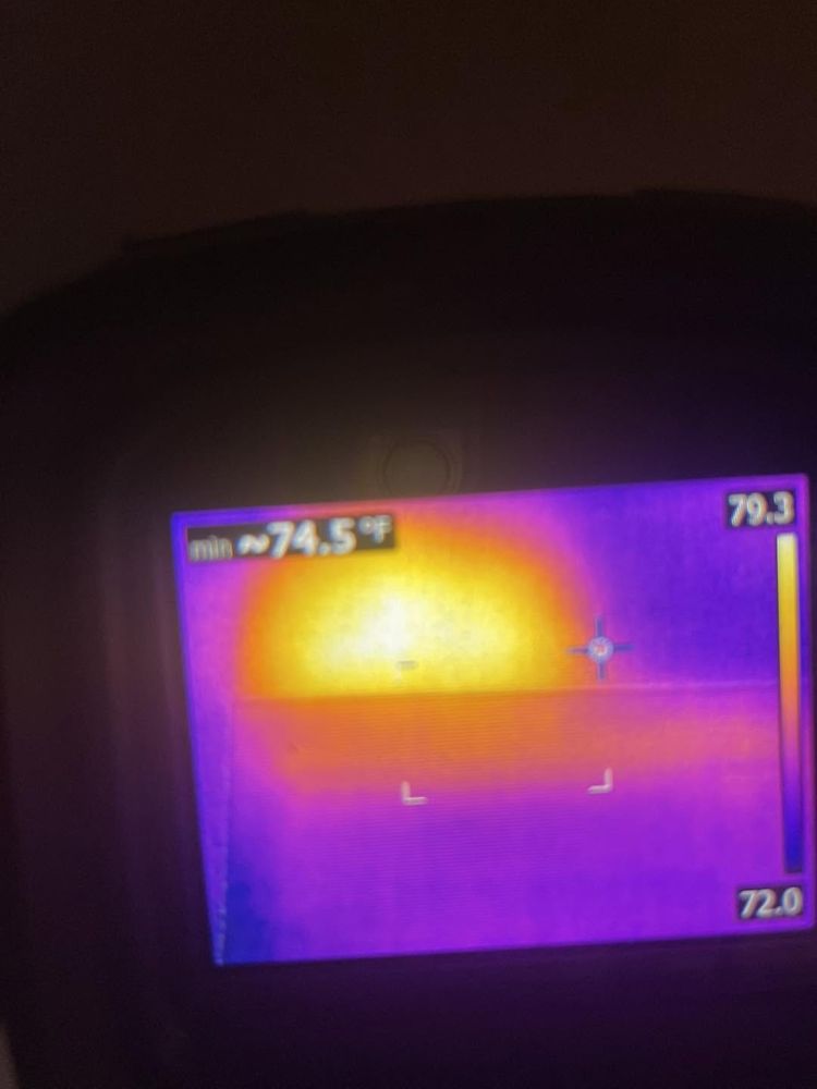 Thermal camera screen showing a bright warm spot on a wall where a yellow jacket nest is hidden